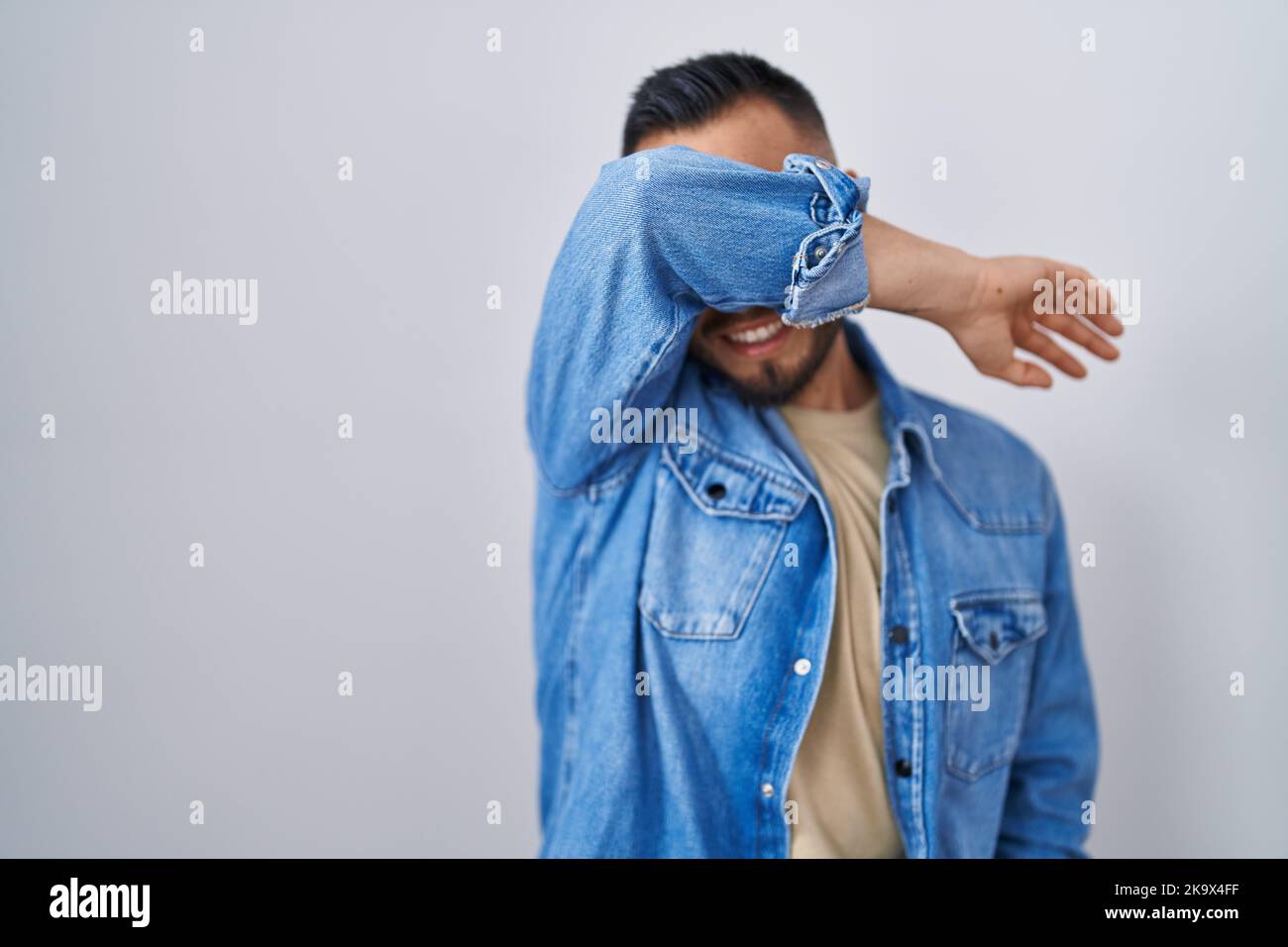 Young hispanic man standing over isolated background covering eyes with ...