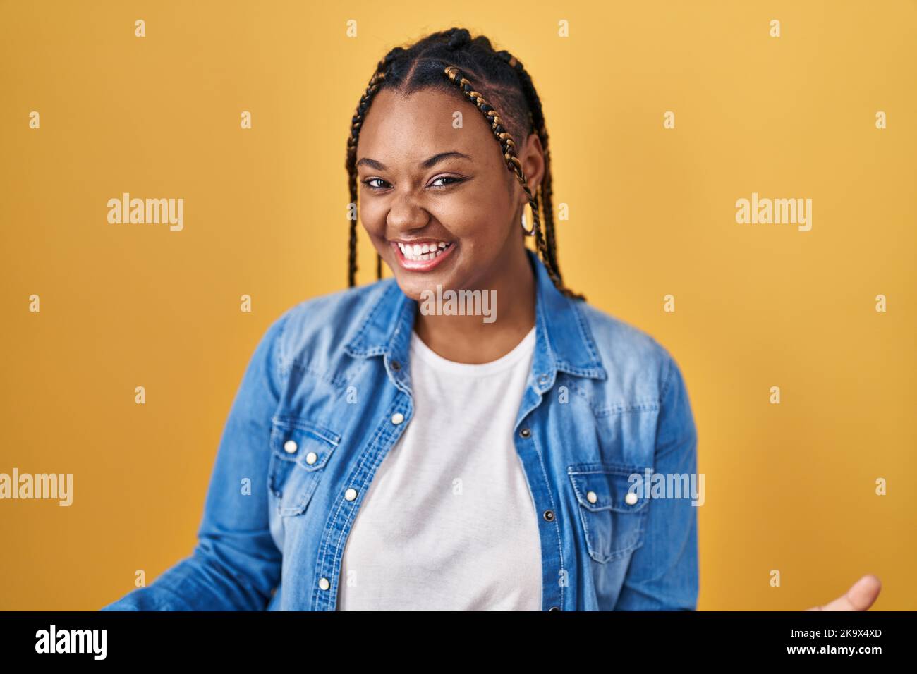 African american woman with braids standing over yellow background ...
