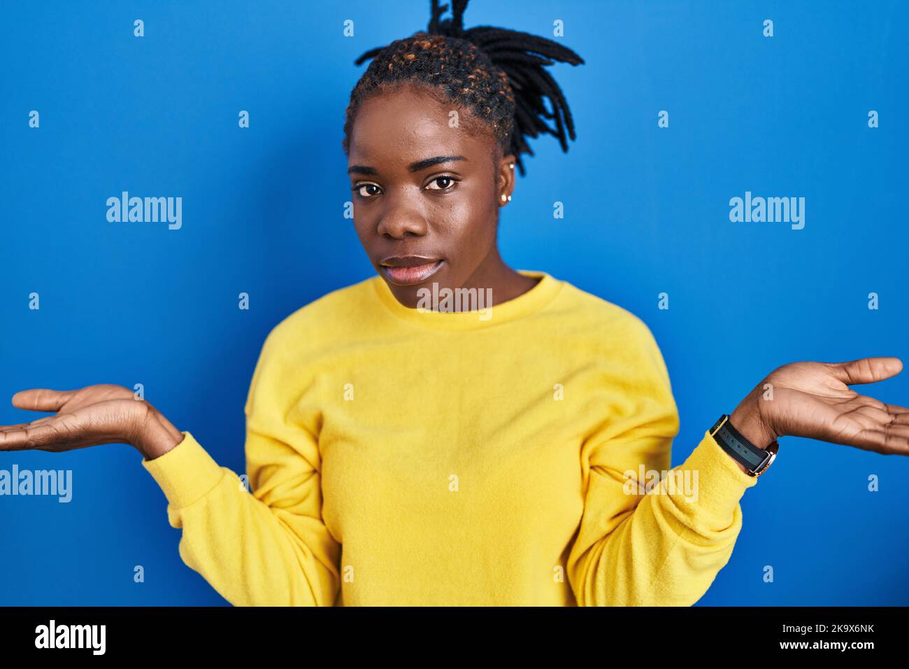 Beautiful Black Woman Standing Over Blue Background Clueless And Confused With Open Arms No 9490