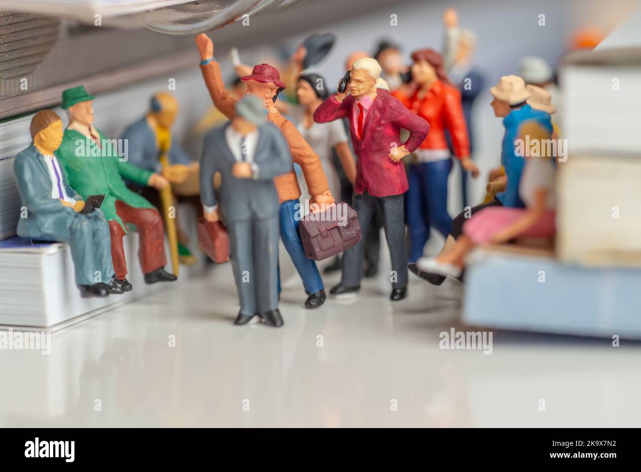 Miniature toys of man and woman with mobile phones talking in a public transportation medium concept - lack of manners Stock Photo