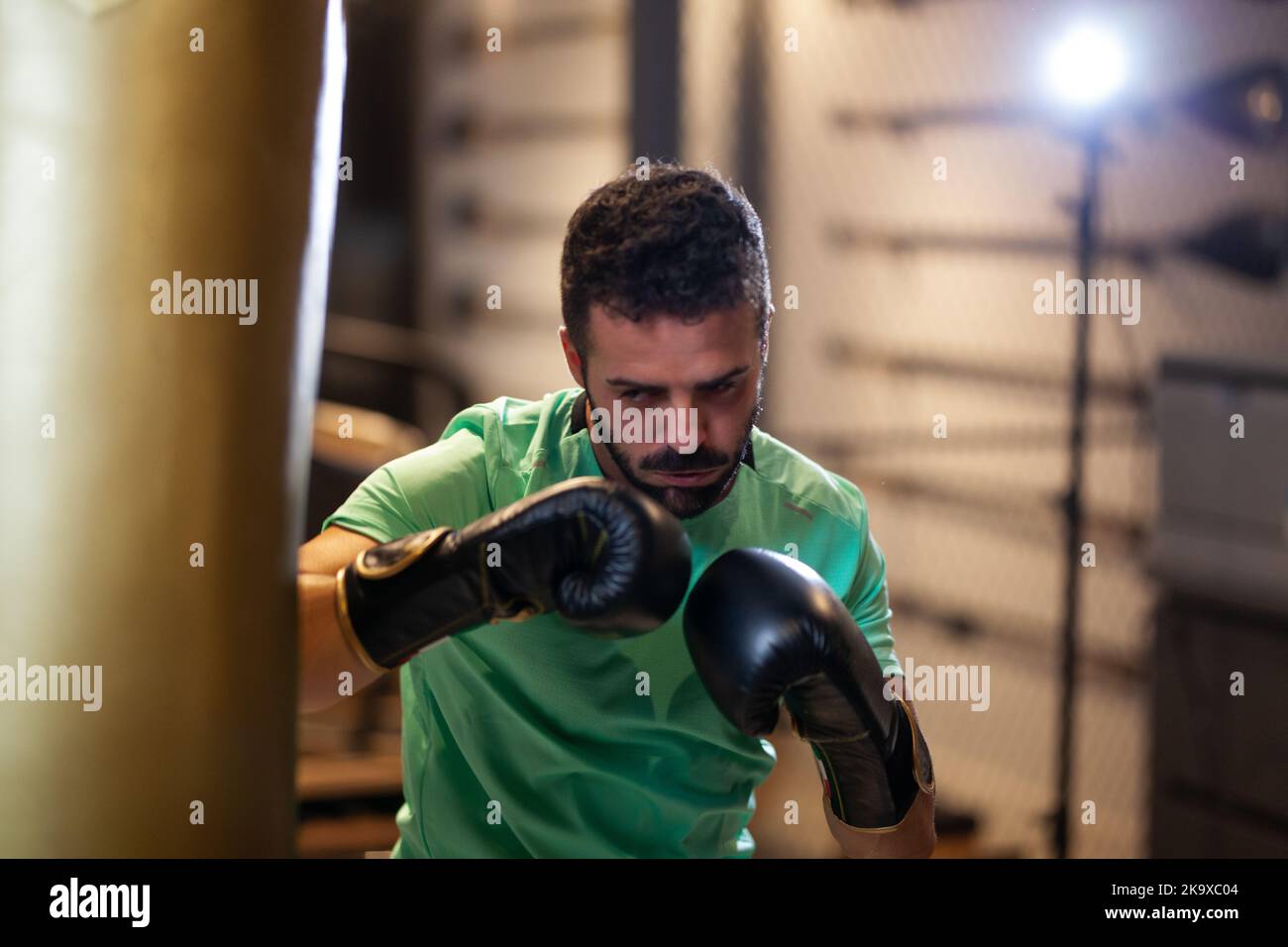 Muscular man with boxing gloves hitting a punching bag in a fitness