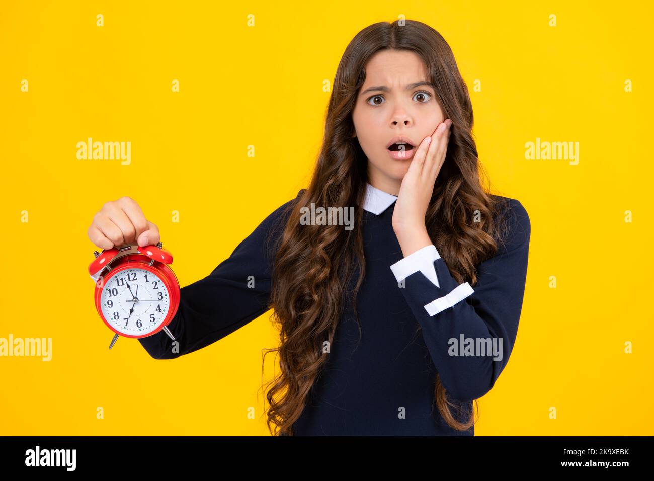 Teen student girl hold clock isolated on yellow background. Time to