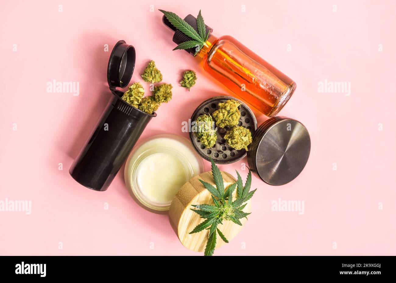 Medical cannabis or Drug, Marijuana flower buds Cannabis CBD oil, Cosmetic cream and grinder on pink background Stock Photo