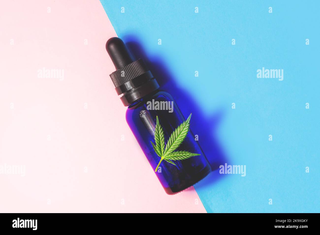 Eyedropper bottle with Cannabis CBD oil and Marijuana leaf on Pink Blue background Stock Photo