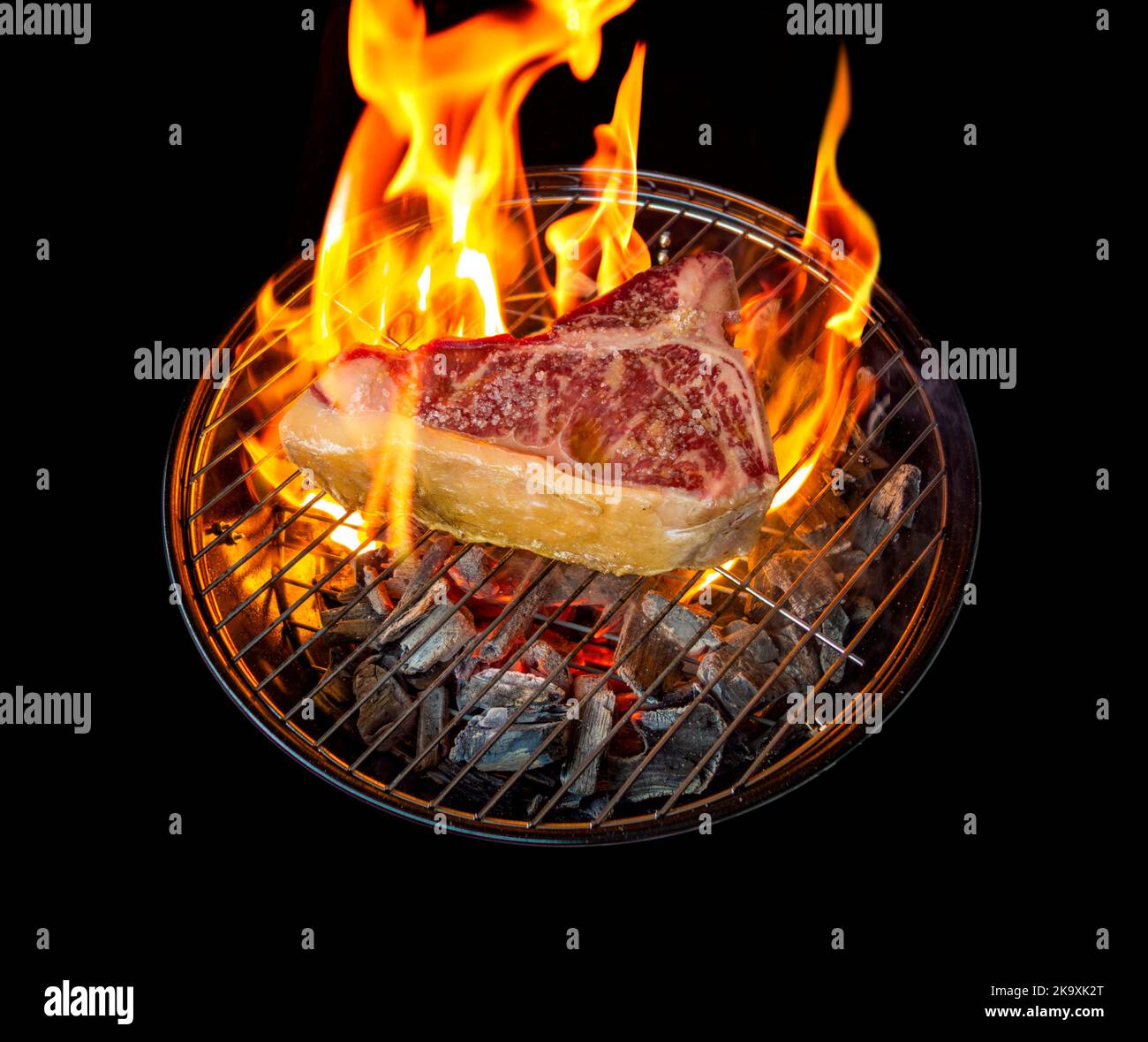Barbecue scenery showing a Tbone steak roasting on a charcoal grill