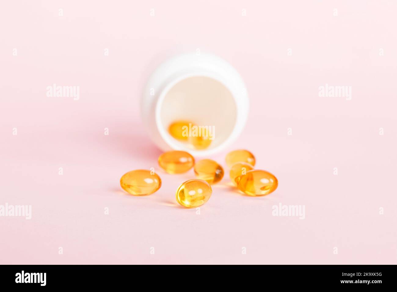 Soft gels pills with Omega3 oil spilling out of pill bottle closeup