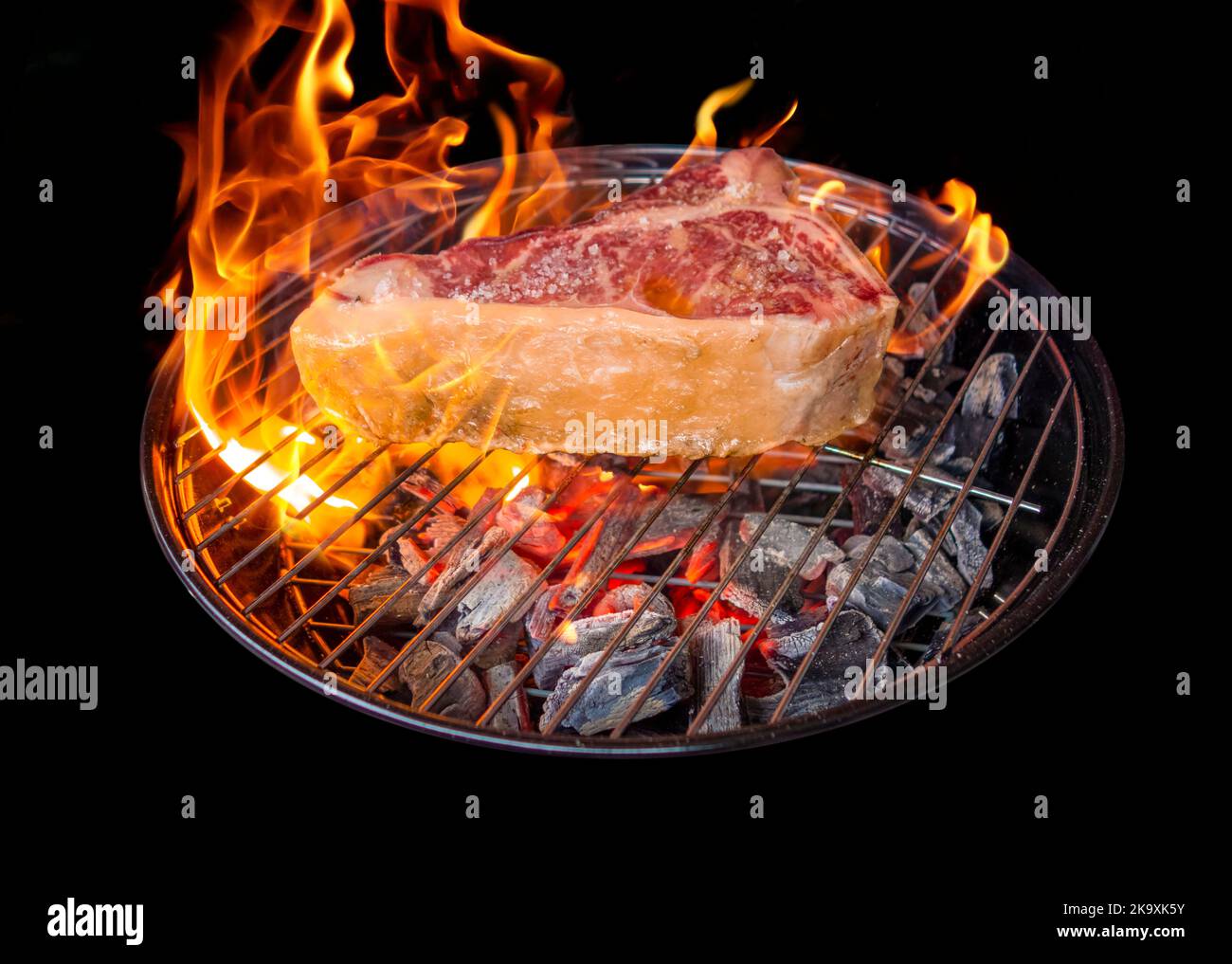 Barbecue scenery showing a Tbone steak roasting on a charcoal grill