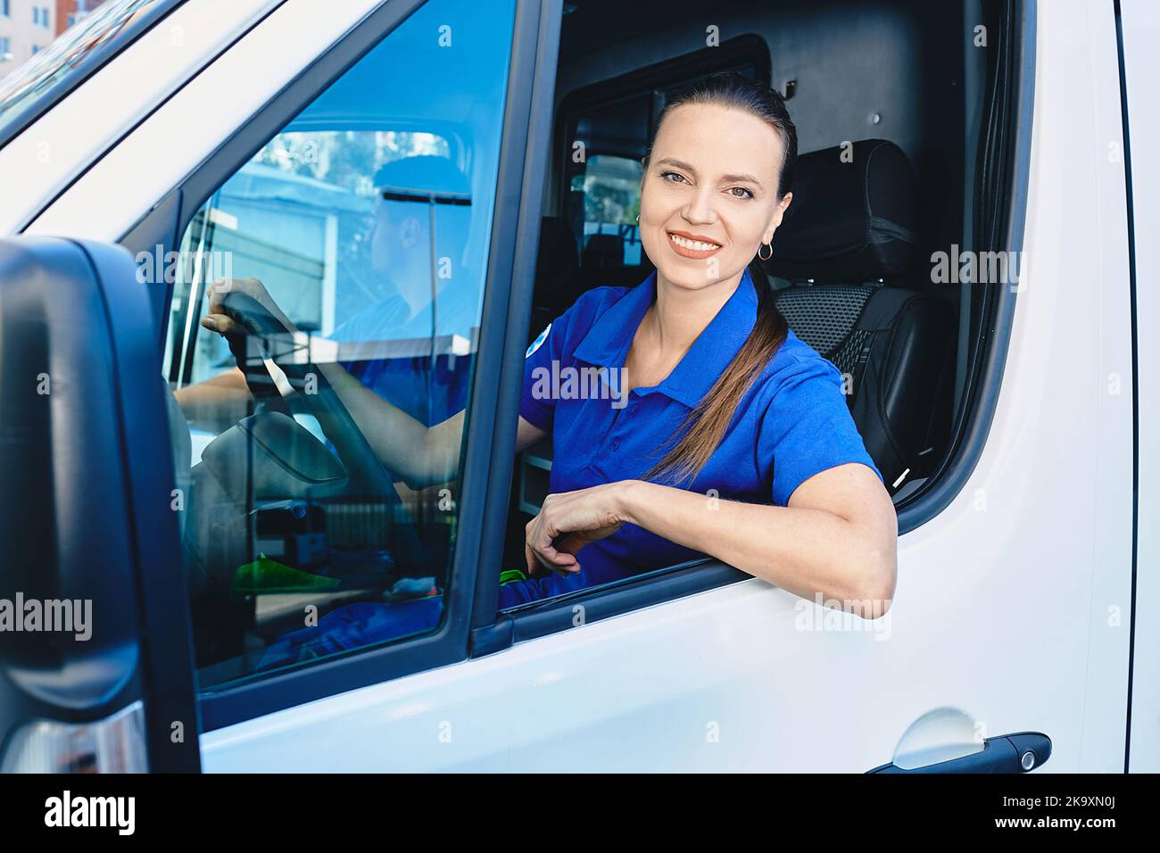 Portrait of female paramedic sitting inside ambulance. EMS worker Stock Photo