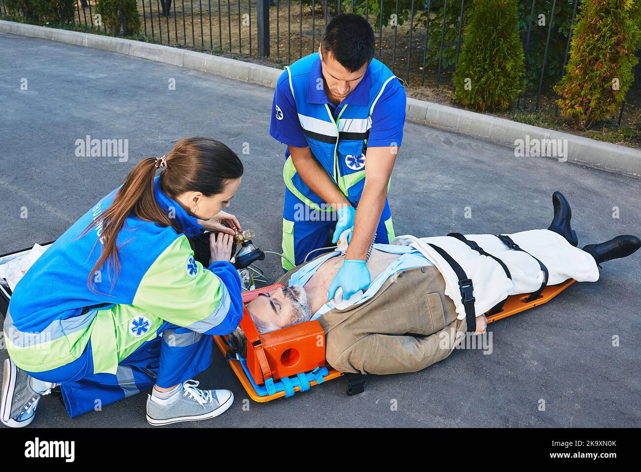 First aid, CPR by rescue workers. Two paramedics performing CPR with mobile defibrillator and manual resuscitator for injury man Stock Photo