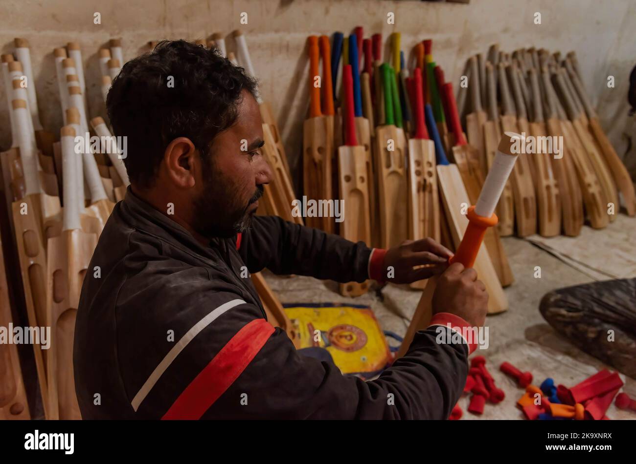 A worker puts grip on a finished bat at a factory in Sangam. Considered ...
