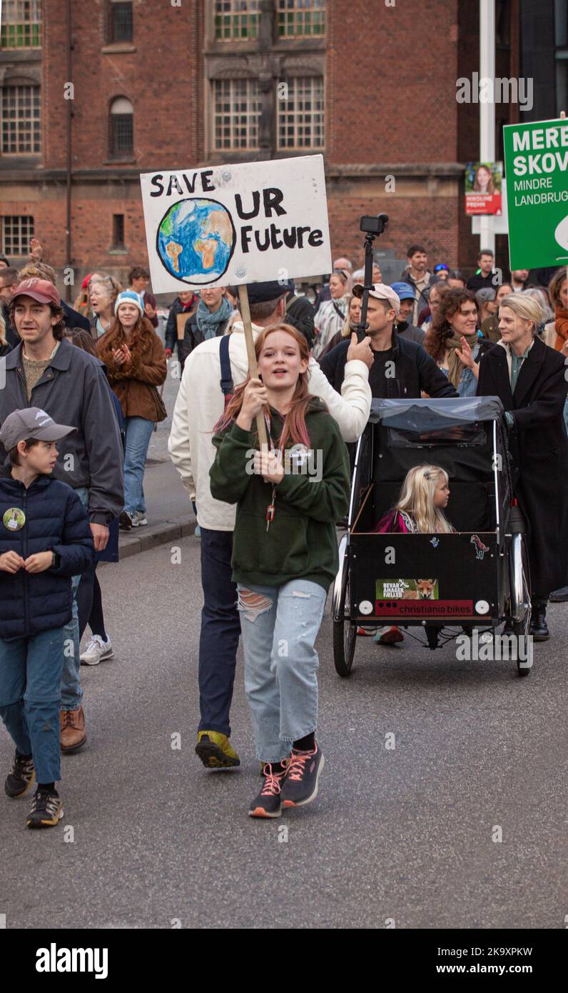 Young girl holding a sign reading Save Our Future with a cartoon drawing of the Earth. In background a cargo bike with a girl. The people s Climate Ma Stock Photo