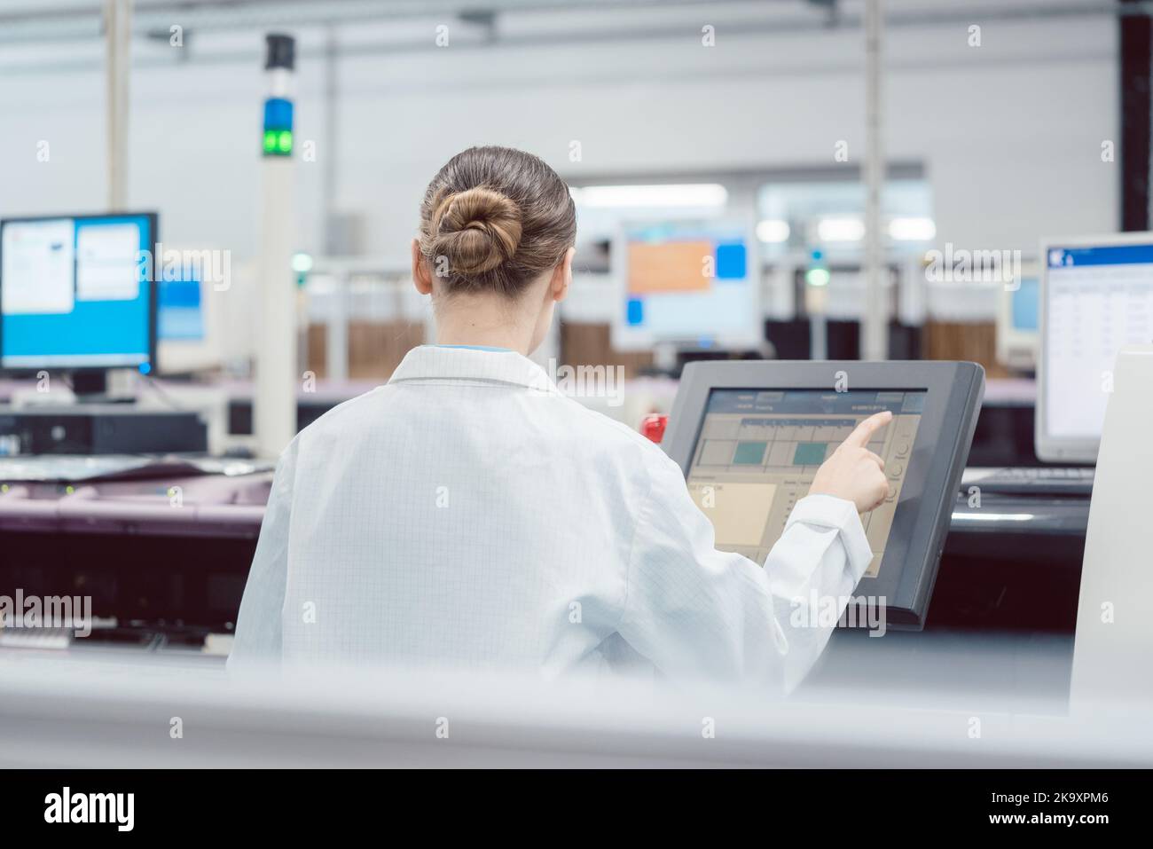 Woman on control compute of assembly line Stock Photo