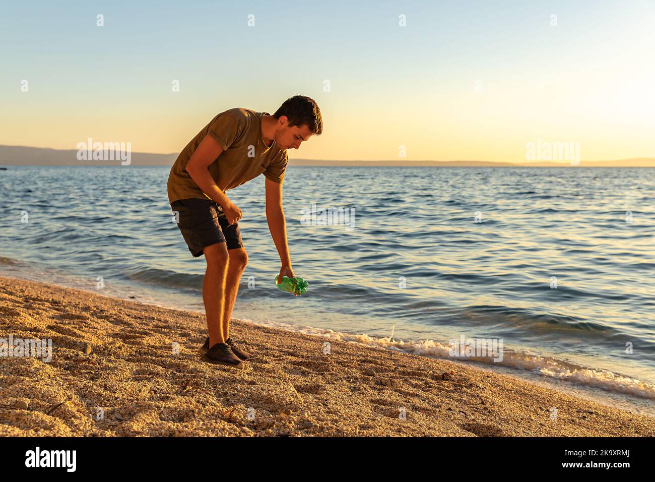 Earth day. Cleanup garbage on the Adriatic sea coast. A boy picking up a plastic bottle on the