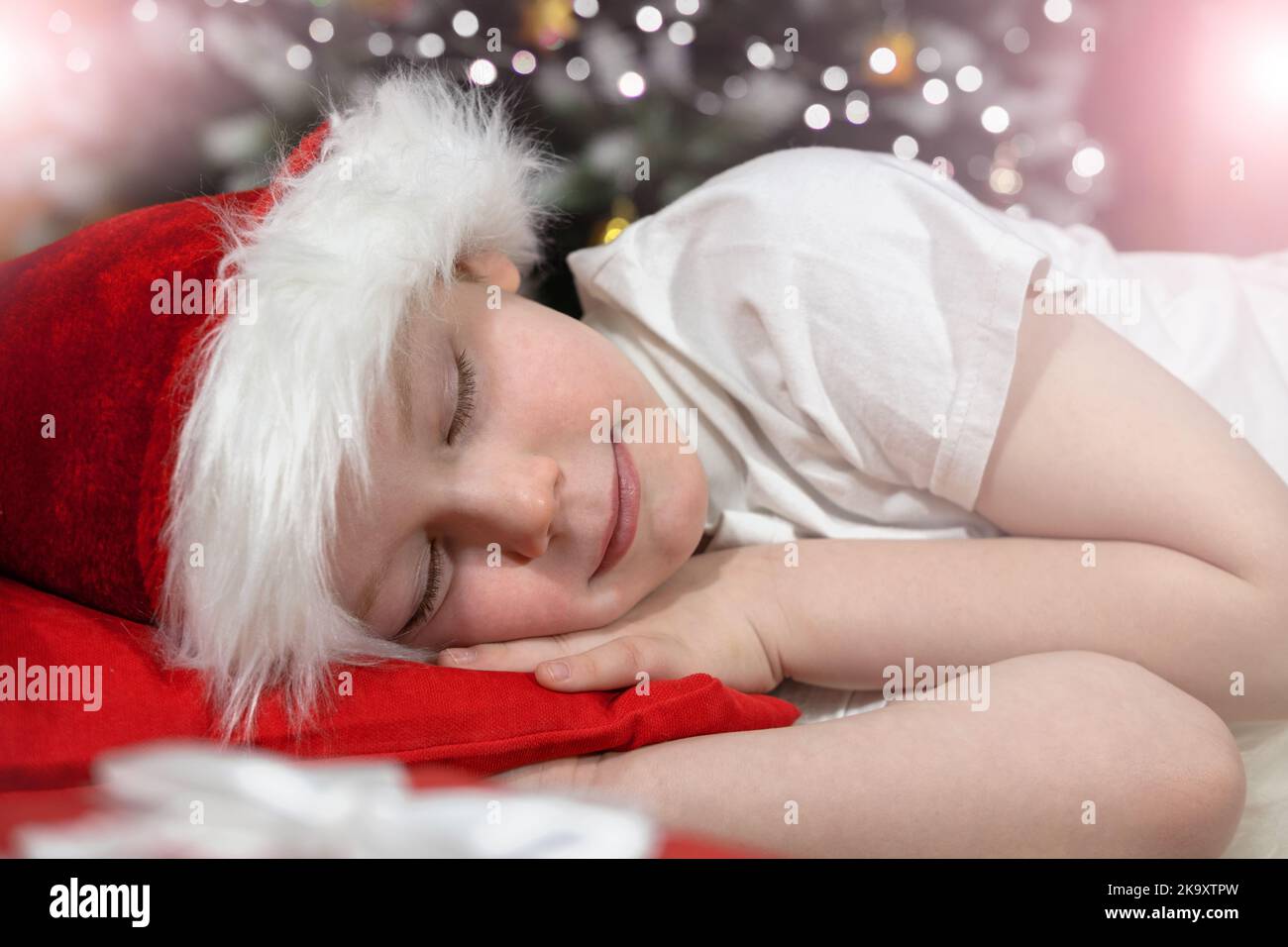 Christmas dreams of a child. A child in a Santa Claus hat sleeps in bed