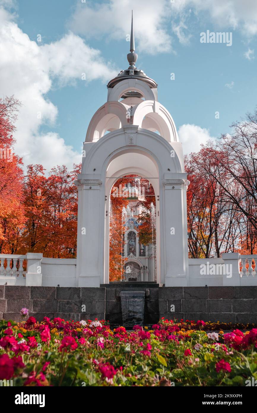 Mirror Stream alcove with flowers, fountain and Myrrh-bearing church in colorful autumnal Kharkiv city center park, Ukraine. Color graded Stock Photo