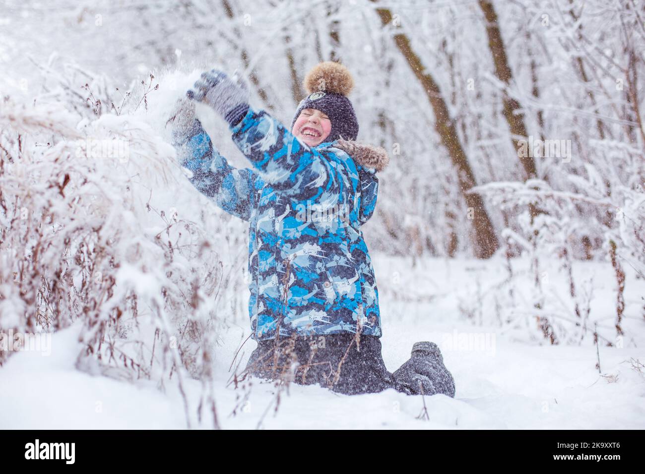boy throwing snow in the air at sunny winter day, back view Stock Photo