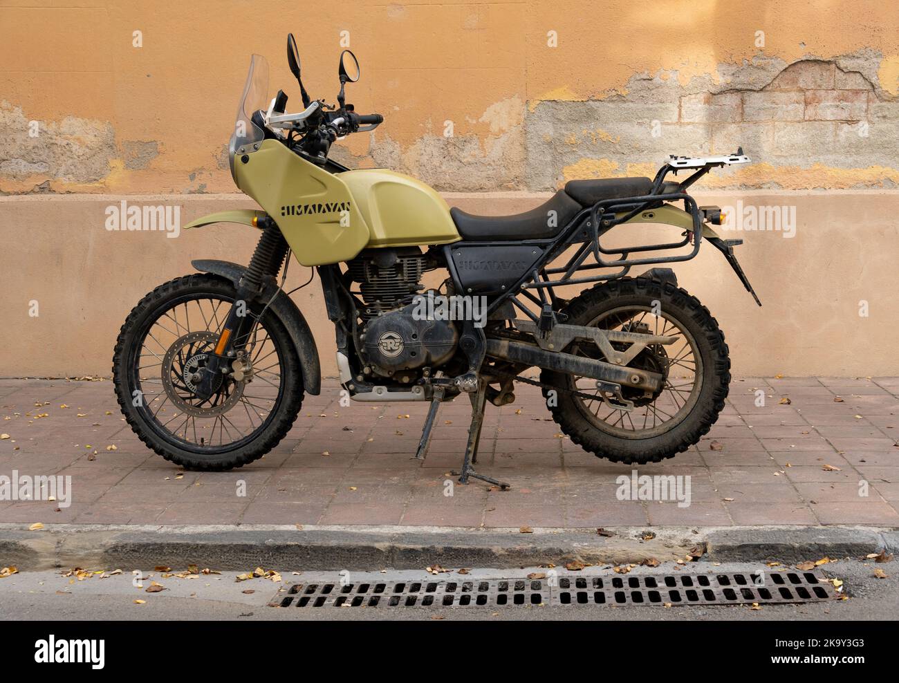 Barcelona, Spain - October 23, 2022: A Royal Enfield Himalayan motorcycle with a knobby wheel and mud, parked on the curb Stock Photo