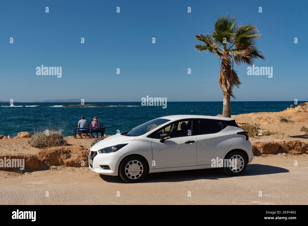 Malia, Crete, Greece. 2022. Holiday couple sitting on a bench on the