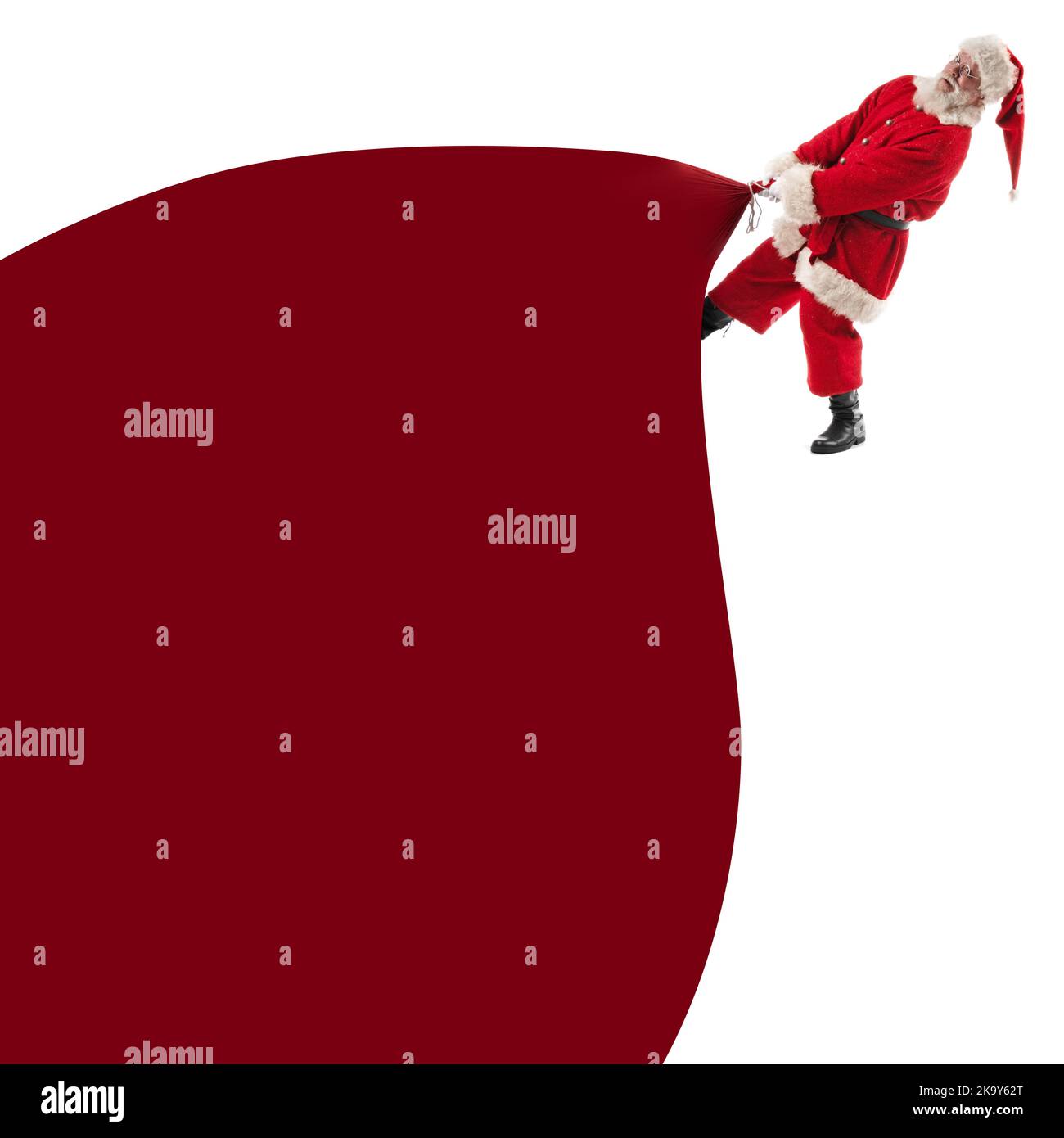 Santa Claus pulling huge bag of gifts isolated on white with copy space ...