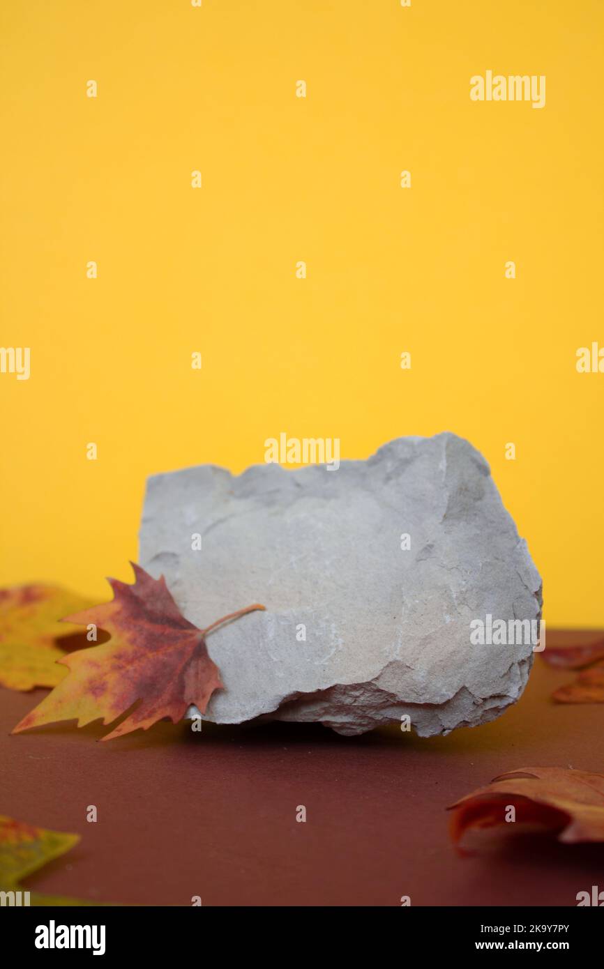 Podium made of stone on an orange background with autumn leaves, space for text, free space Stock Photo