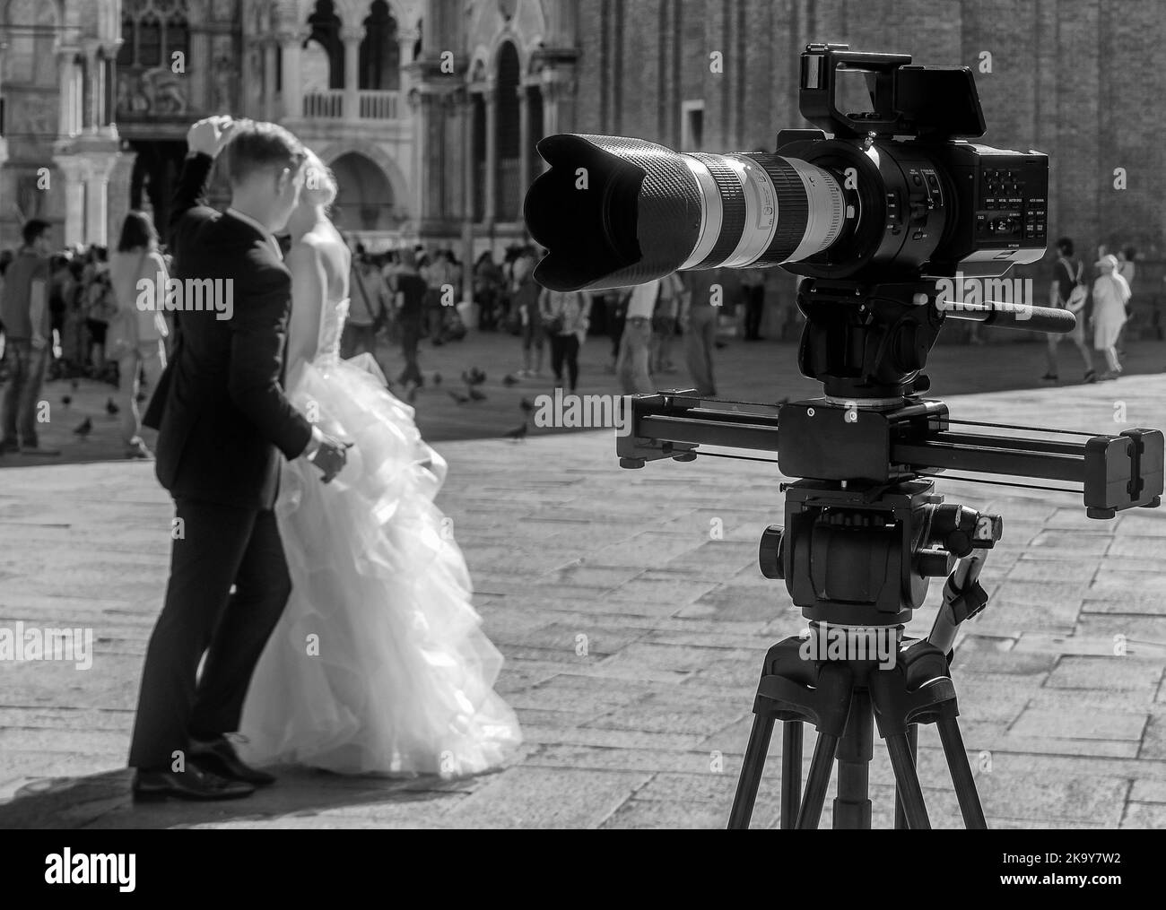 A young newlywed couple dances in Piazza San Marco, Venice, Italy, filmed by a camera, in black and white Stock Photo