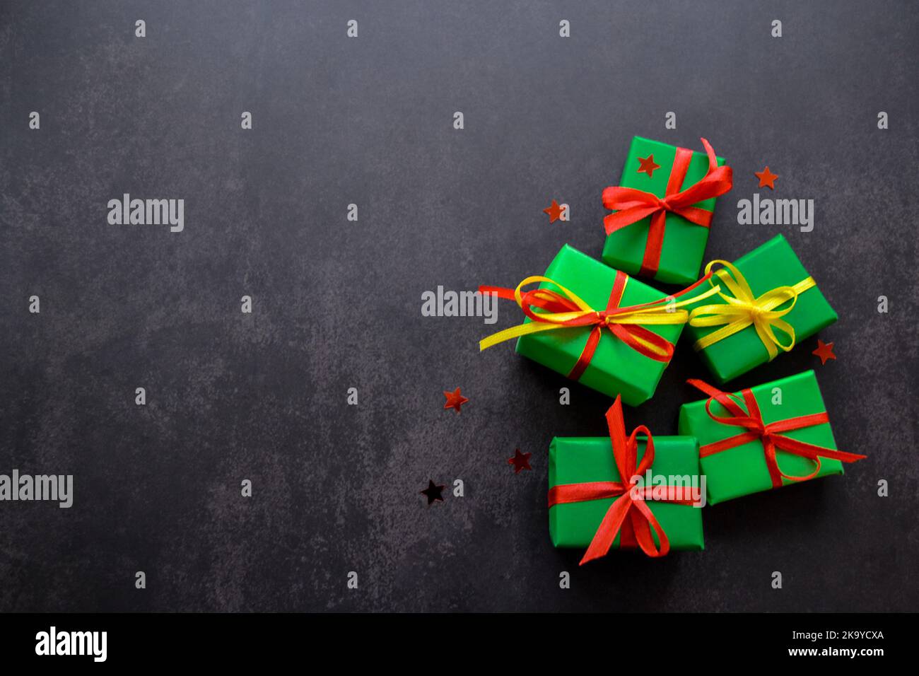 Gifts in green paper with red and yellow ribbons lie next to each other