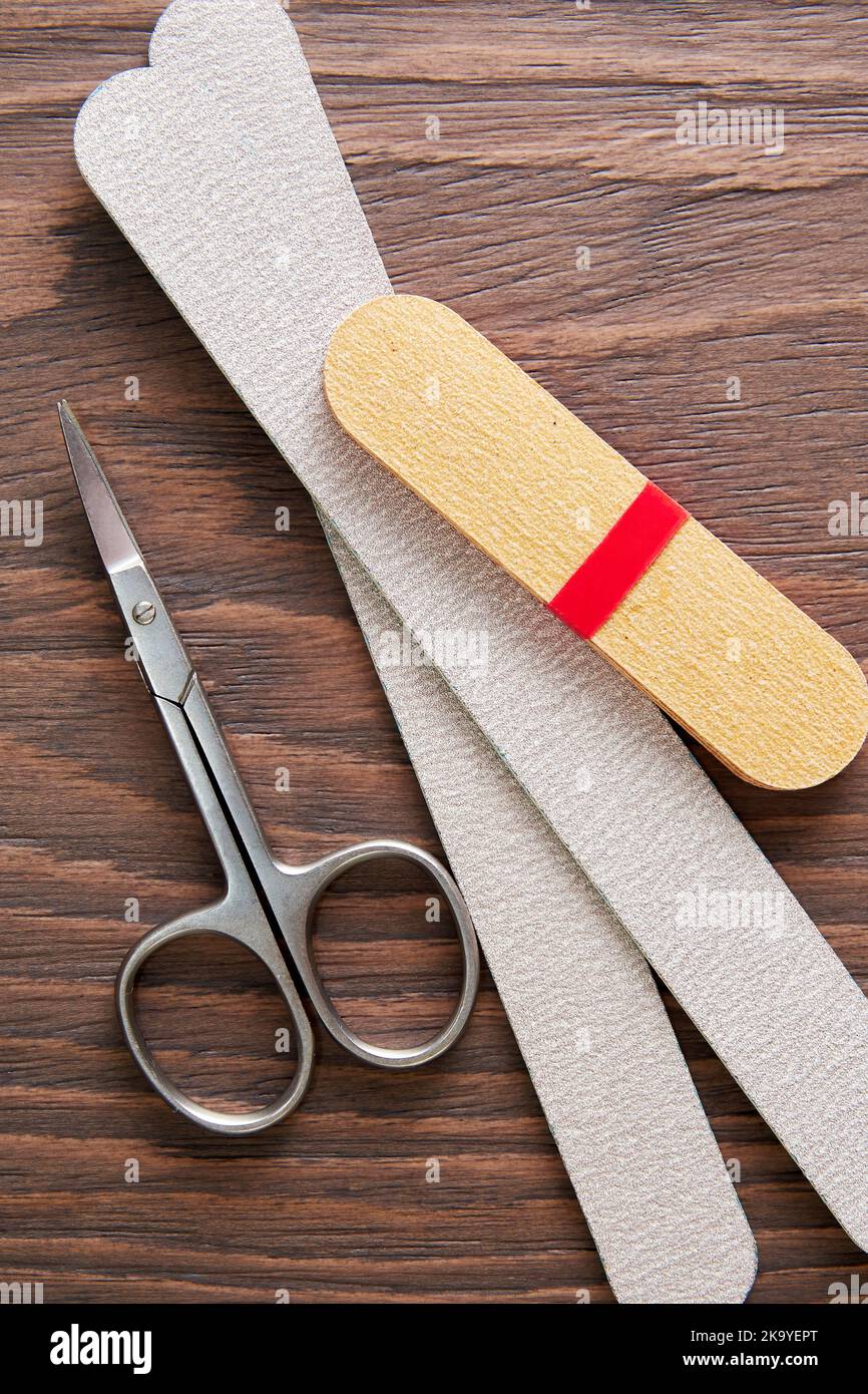 Flat lay mockup with manicure tools, scissors, nail file, cotton pad on the worker table. Health and body care backgrounds. Vertical backdrop Stock Photo