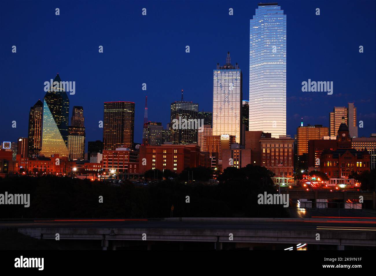 The sunset sky is reflected in the glass and windows of the Dallas Texas skyline at night Stock Photo
