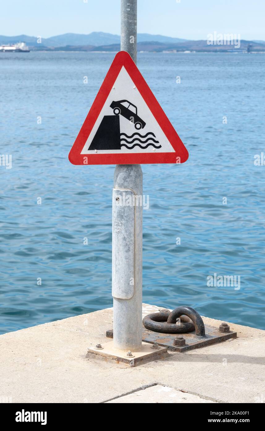 Red triangle warning sign making drivers aware that vehicle could fall into deep water. Stock Photo