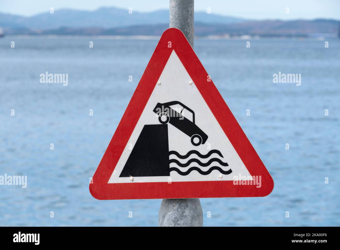 Red triangle warning sign making drivers aware that vehicle could fall into deep water. Stock Photo
