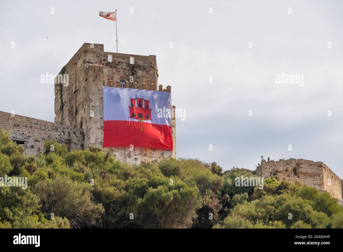 Low angle view of the Moorish Castle on the Upper Rock at Gibraltar, with the Gibraltar flag draped at the front of the historic building. Stock Photo
