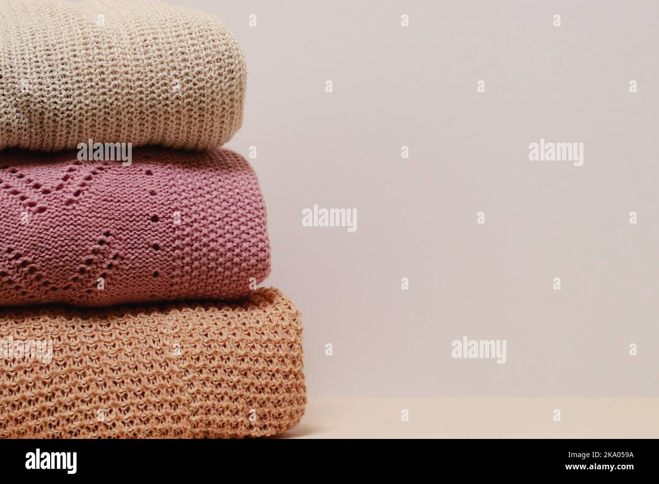 stack of folded knitwear, minimal lifestyle, capsule wardrobe, copy