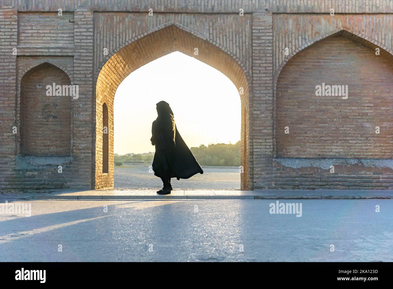 Islamic woman with traditional headscarf and dress on the Khaju bridge in Isfahan, Iran. unidentifiable silhouette like shape of iranian woman Stock Photo