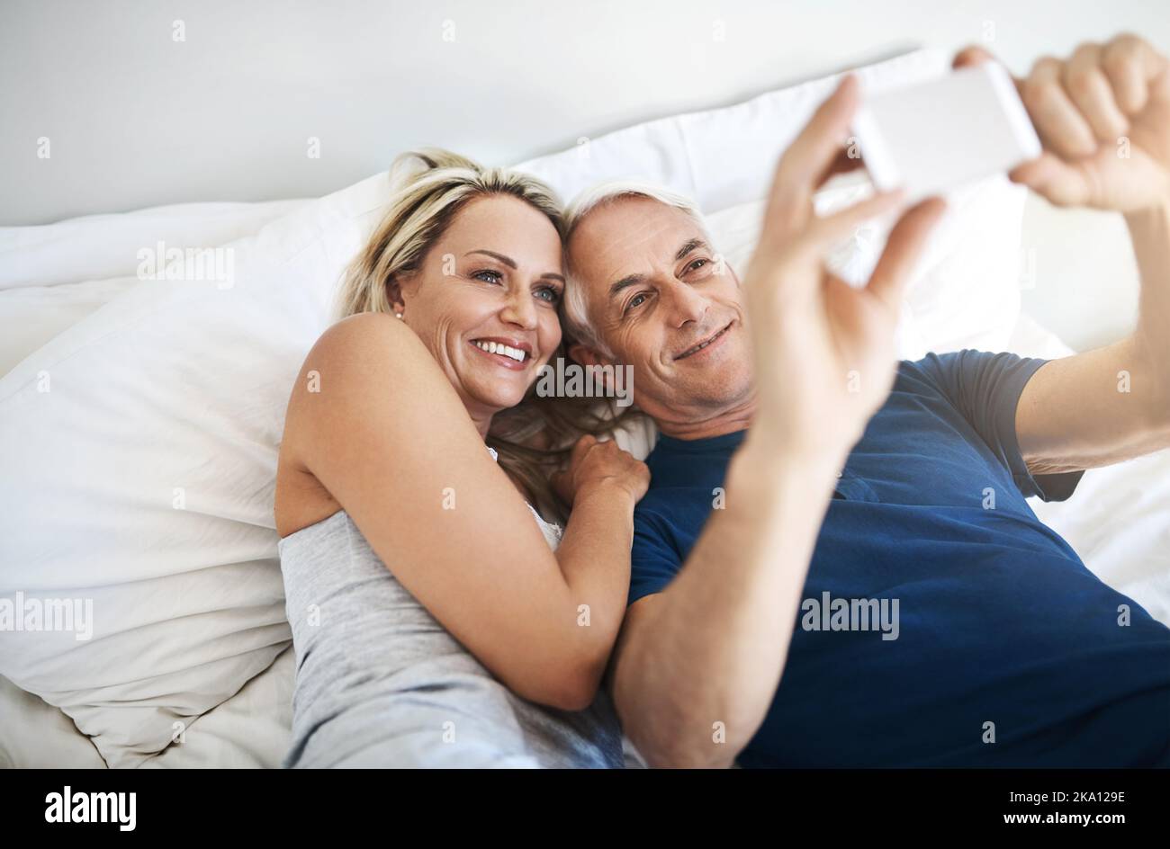 Capturing moments of love. an affectionate mature couple taking selfies in bed together at home. Stock Photo