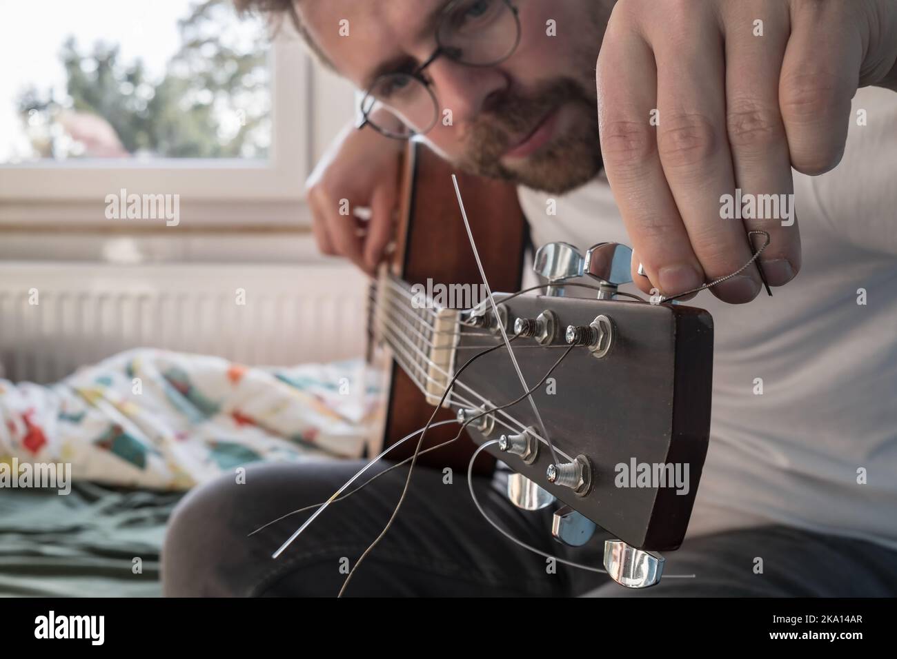 Acoustic guitar tuning. Focused man repairs a stringed musical