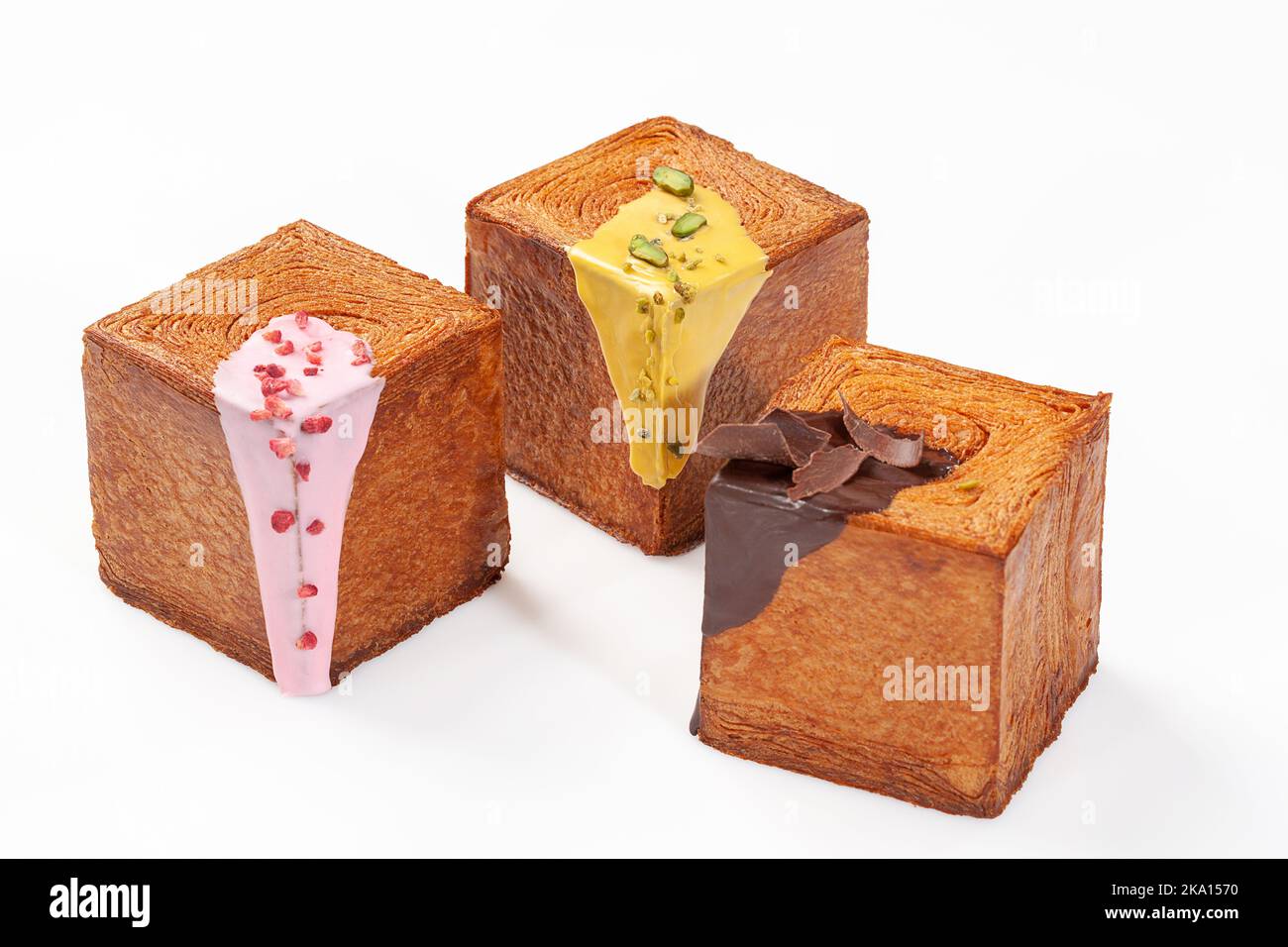 Three cube shaped croissants with creamy berry glaze, pistachio sauce and chocolate ganache Stock Photo