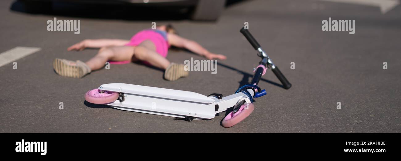 Girl lies on pavement after collision with cars on scooter Stock Photo