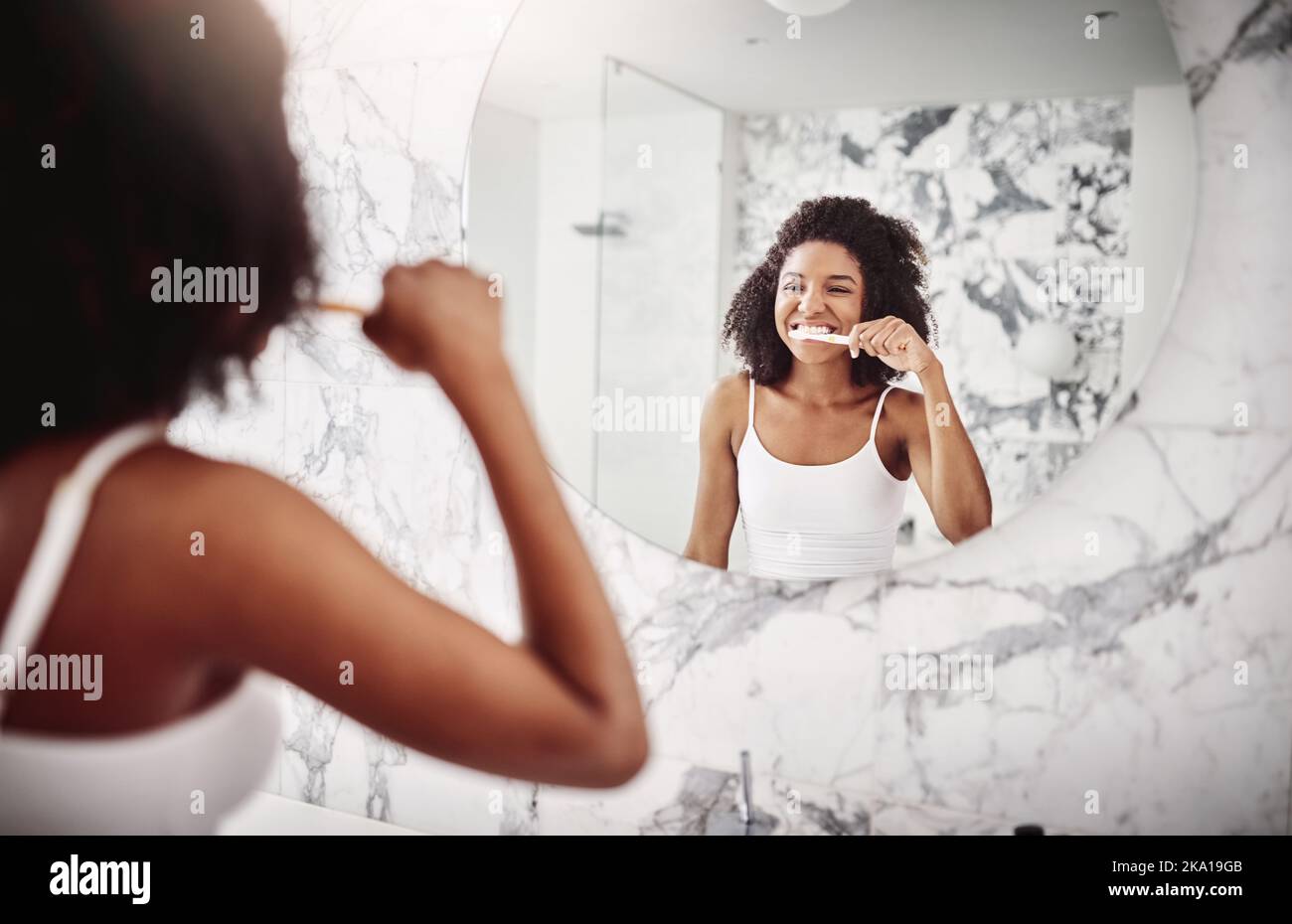 Brushing your teeth is a form of healthy living. an attractive young woman brushing her teeth in the bathroom at home. Stock Photo