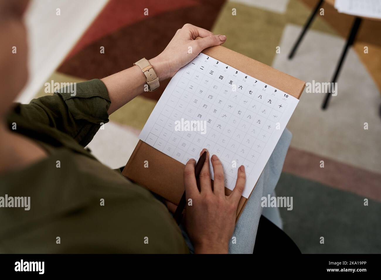 Above angle of female tutor with spreadsheet of Chinese hieroglyphs checking paper of student or explaining new subject at lesson Stock Photo