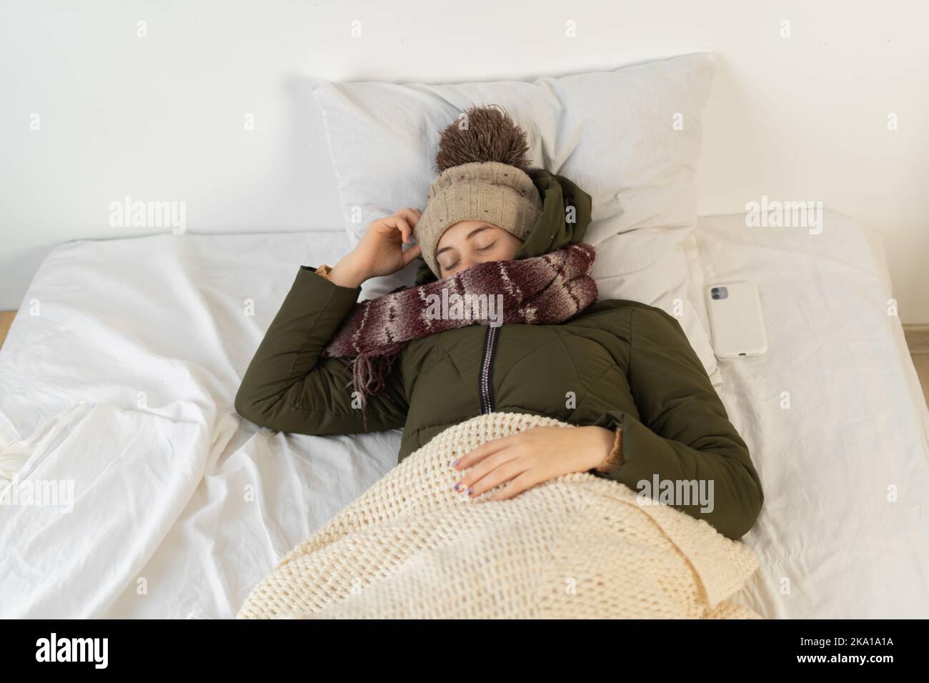 Sleeping woman feeling cold wearing warm winter clothes indoors. broke