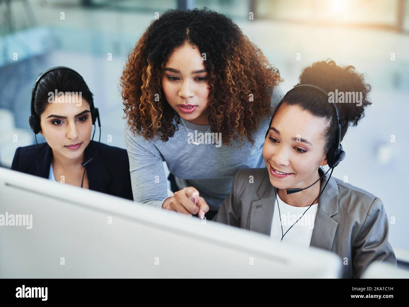 Working together to resolve your issues with speed. a young woman assisting her colleagues in a call centre. Stock Photo
