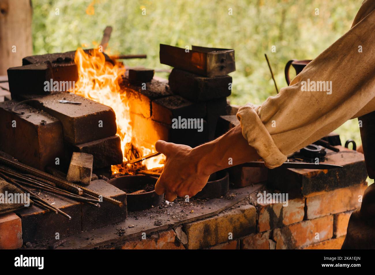A blacksmith hardens steel at high temperature in a homemade furnace in the village Stock Photo