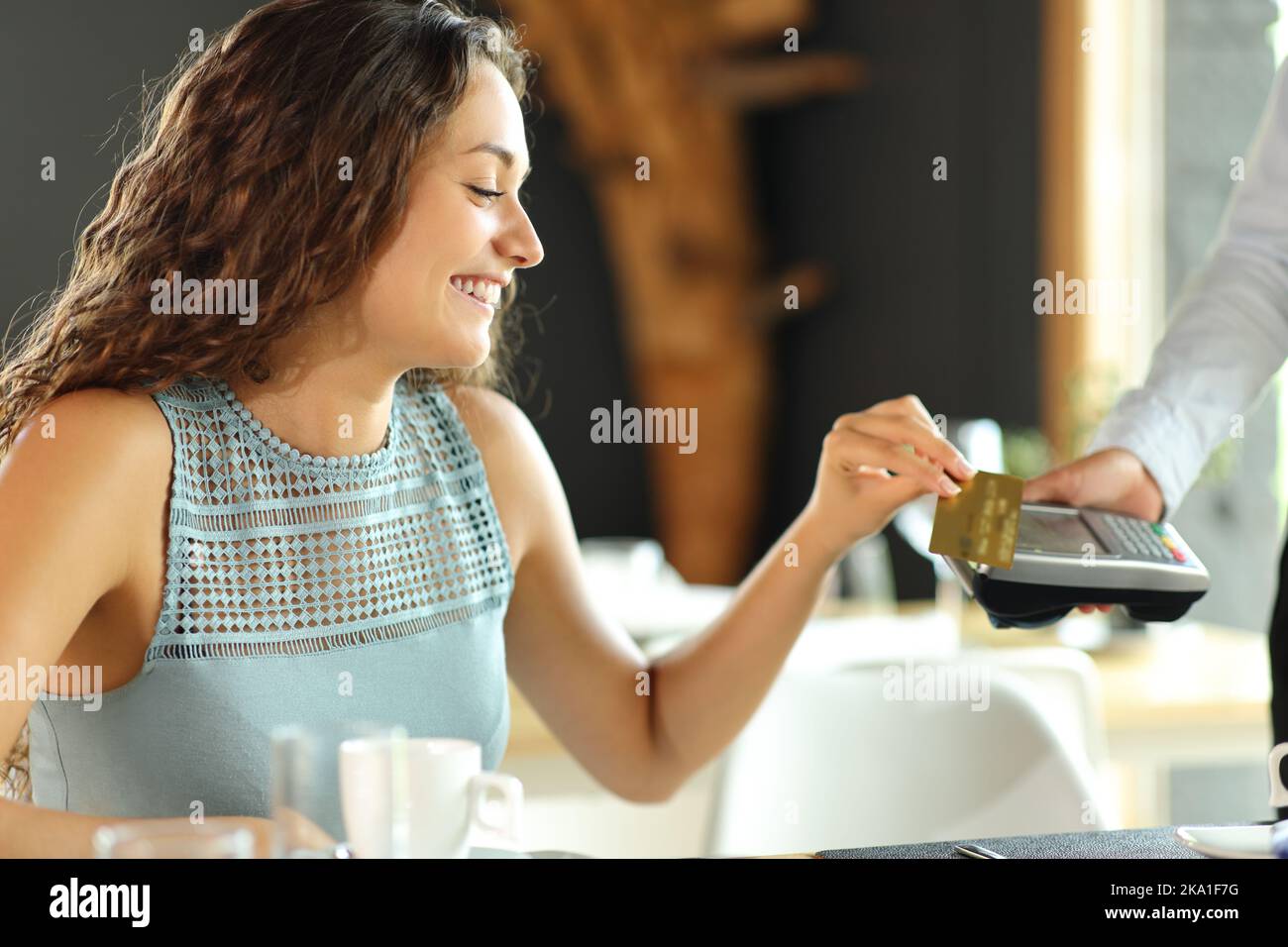 Happy customer in a restaurant paying with credit card Stock Photo