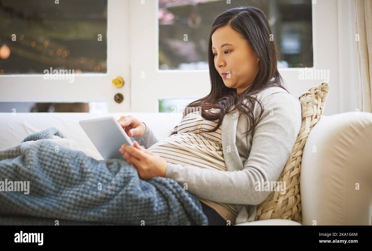 Browsing through a range of pregnancy tips and advice. a pregnant woman using a digital tablet at home. Stock Photo