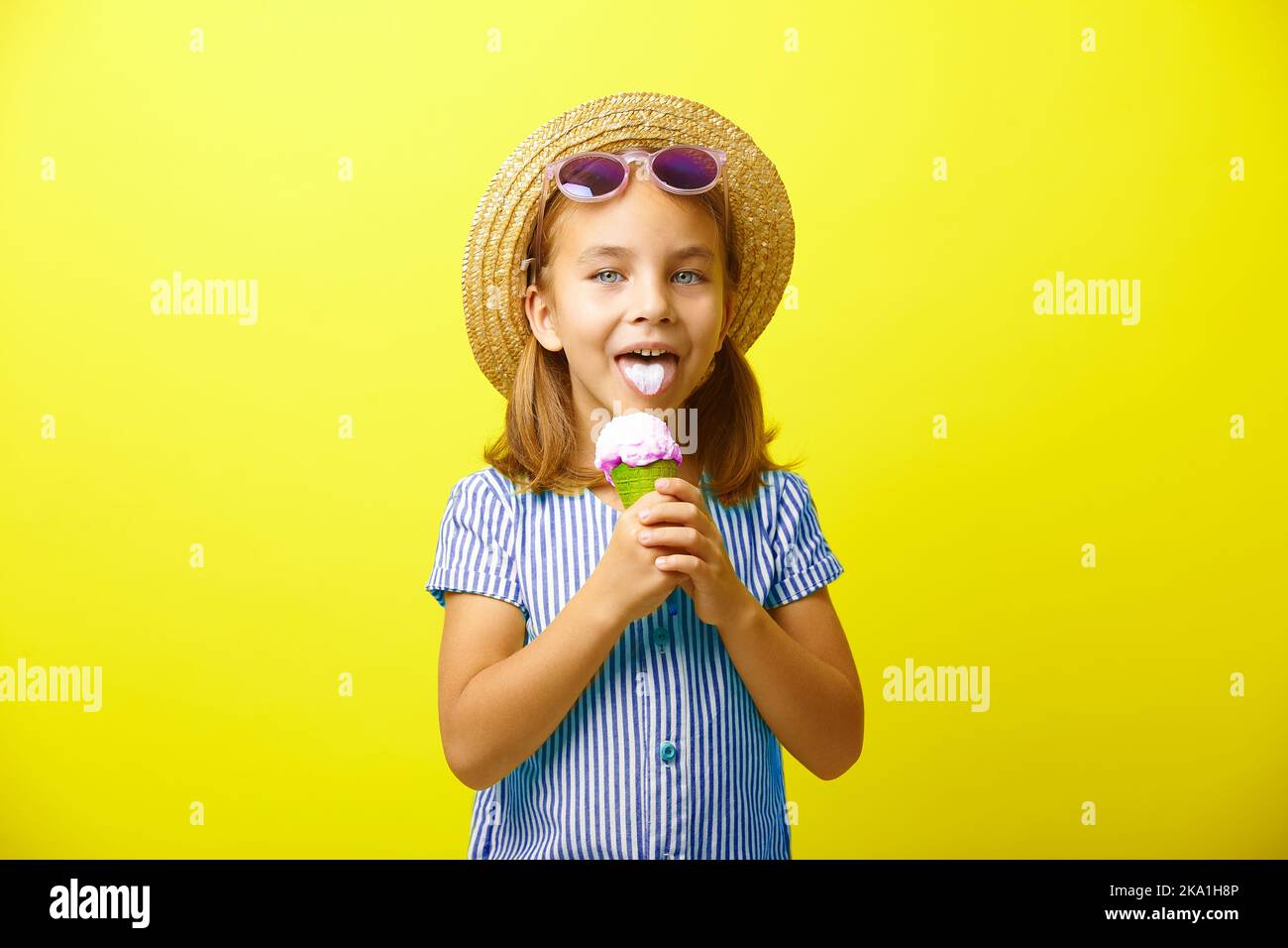 Cheerful little girl with ice cream on yellow isolated background. Stock Photo