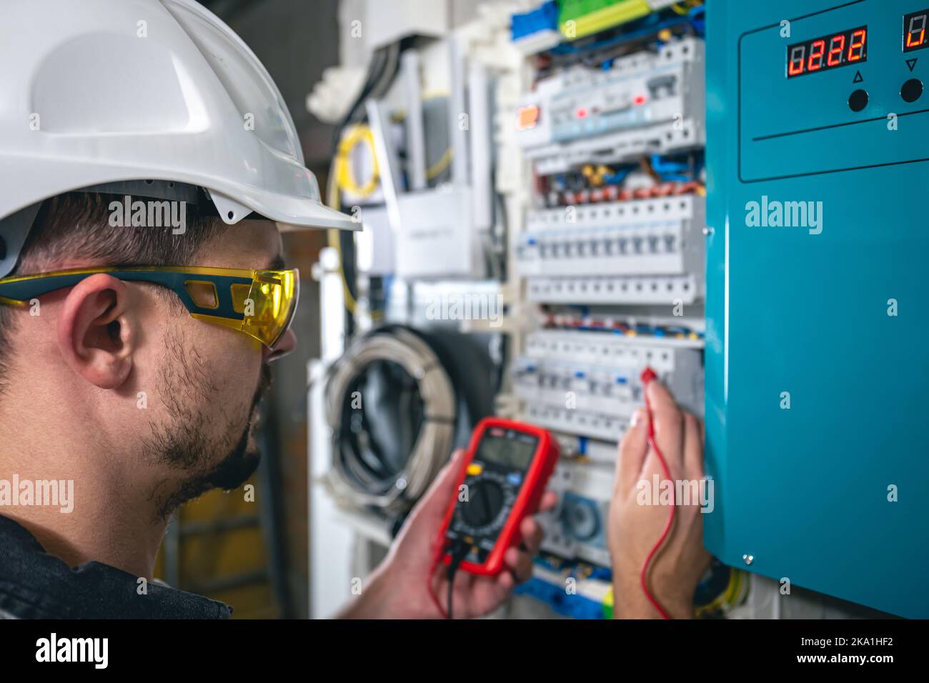 Man, an electrical technician working in a switchboard with fuses. Stock Photo