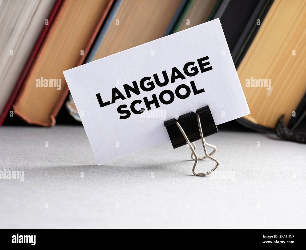 The word language school written on a business card with books background. Foreign language education concept. Stock Photo