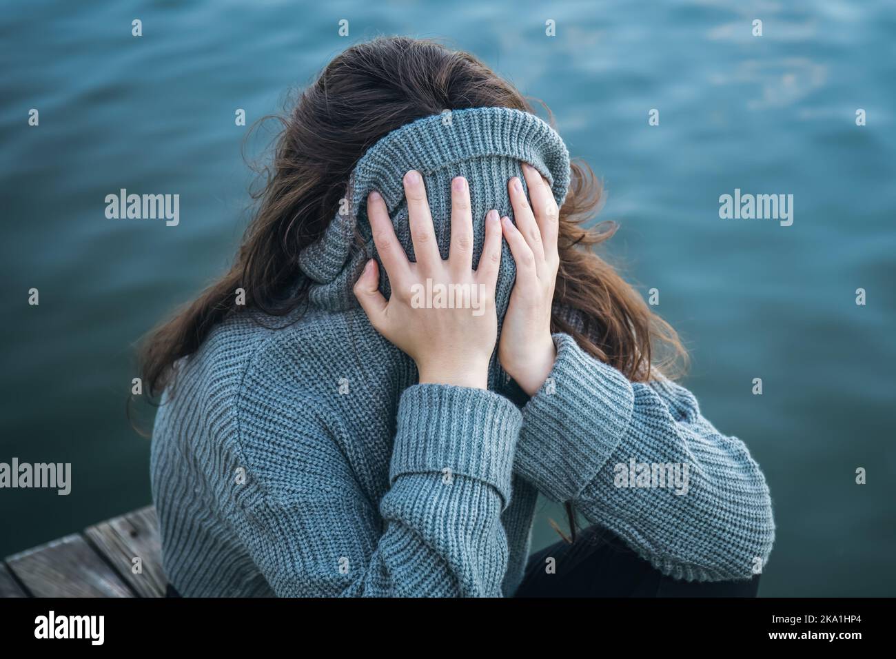 The woman hid her face in a sweater, sitting by the sea Stock Photo - Alamy