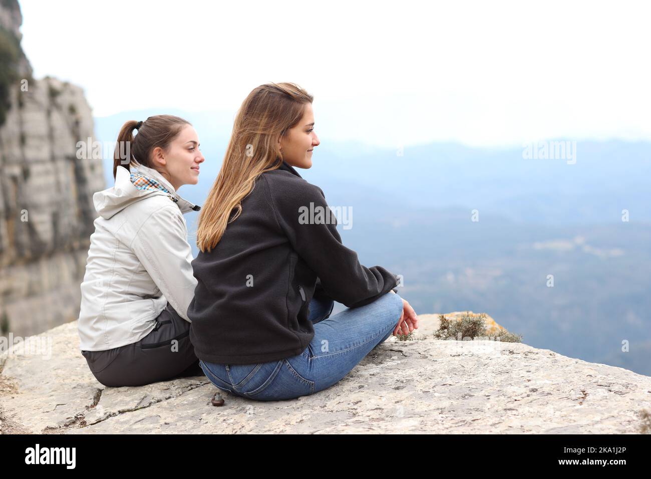 Two trekkers contemplating views sitting from cliff Stock Photo