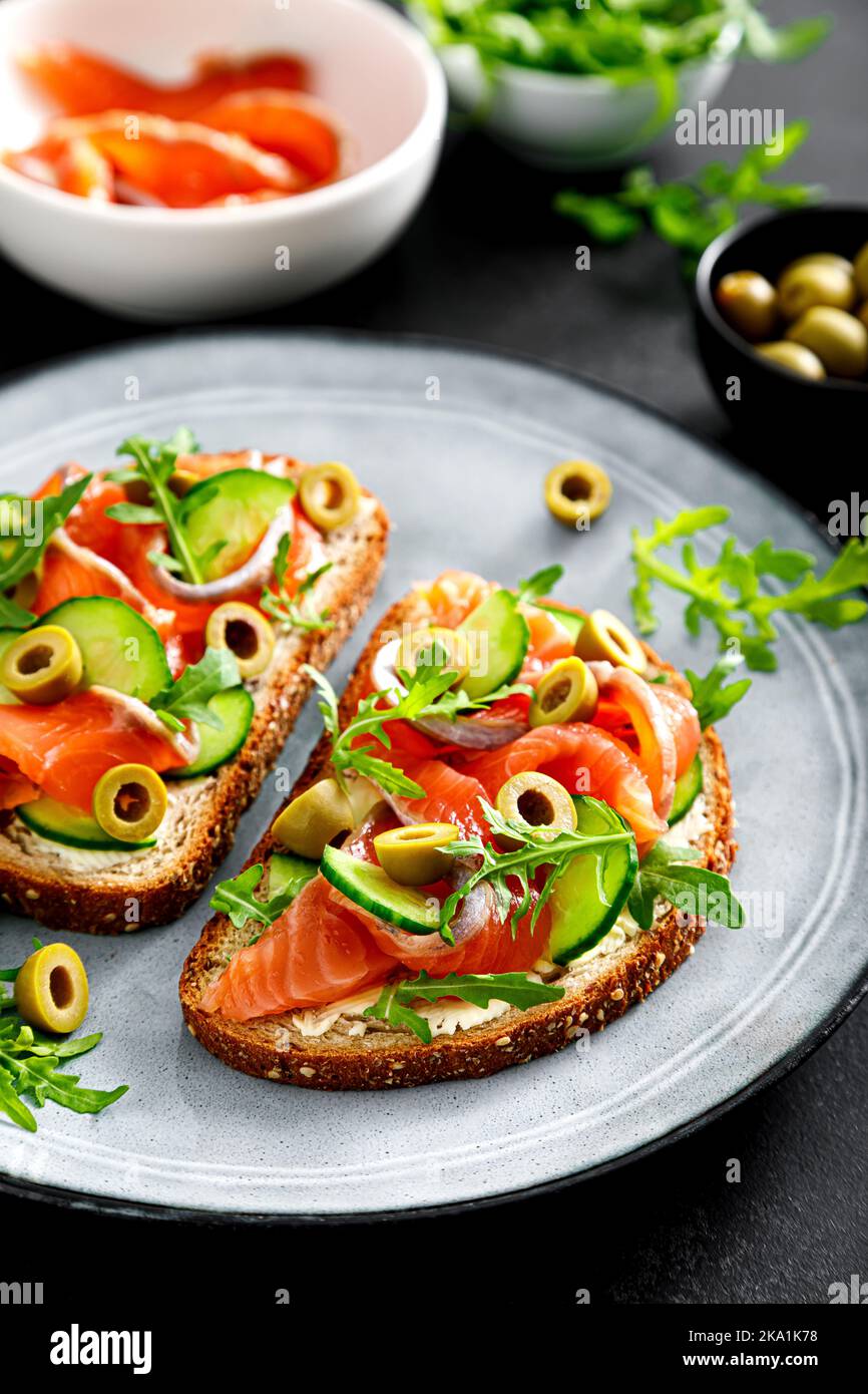 Toasts with salted salmon, arugula, green olives and cucumber Stock Photo